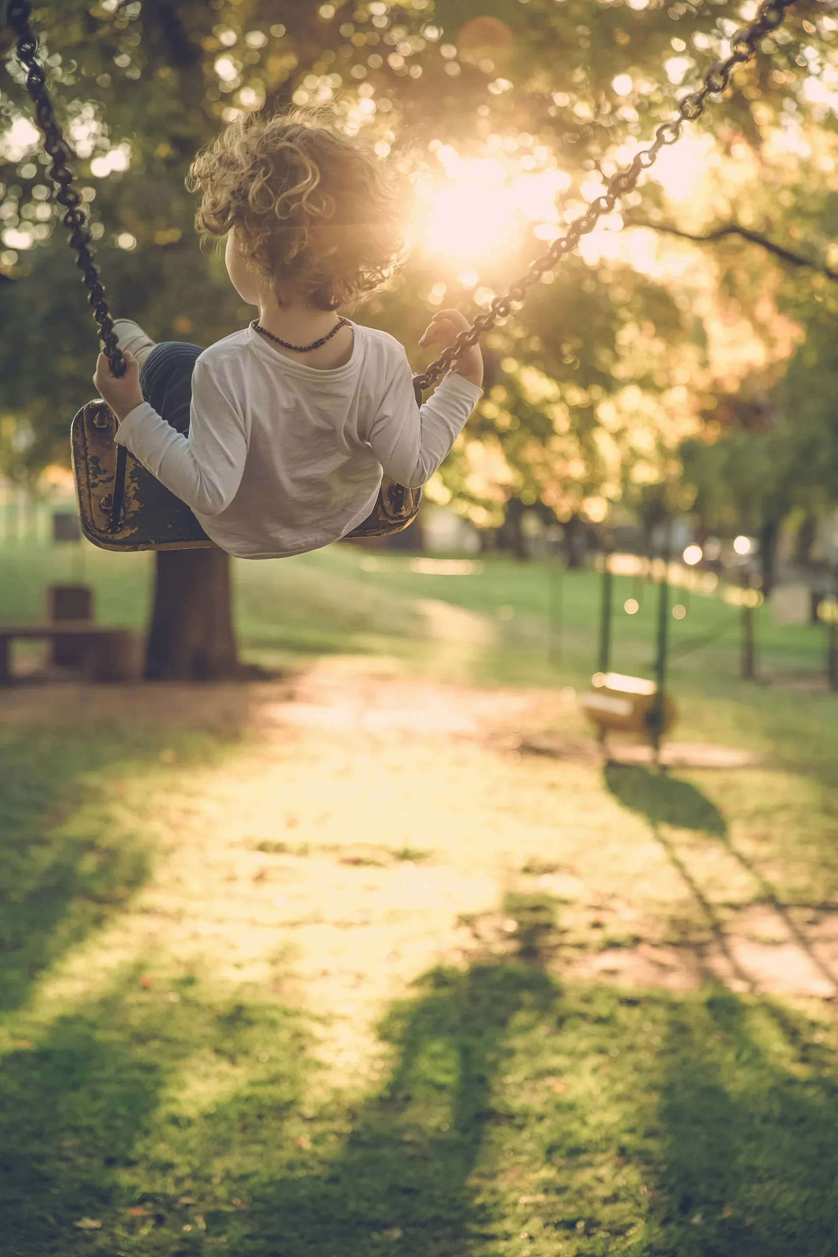 Child playing on a swing in a sunny park near the Live at Finestra community in Grandview Heights, South Surrey
